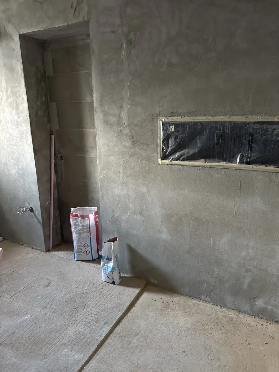 Hrubá stavba koupelny — betonové zdi a okno, Berounsko