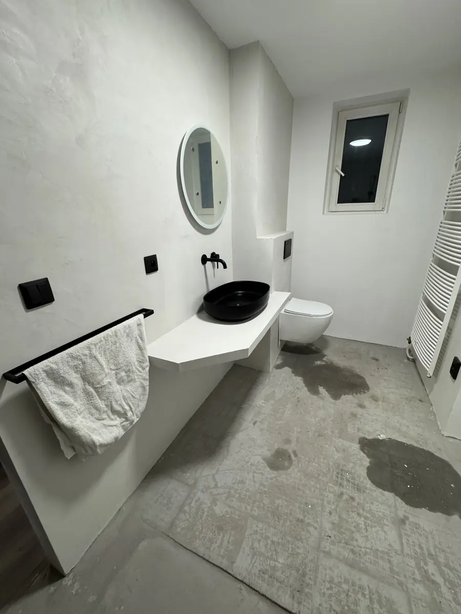 Hotová moderní koupelna — černé umyvadlo, bílé stěrky a závěsné WC, Berounsko